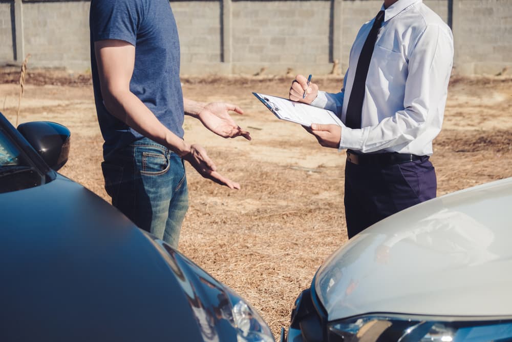 Insurance agent discussing with car owner for accident claim and processed.